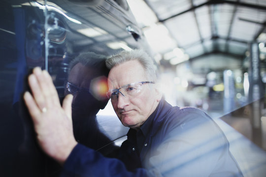 Focused male mechanic examining car in auto repair shop