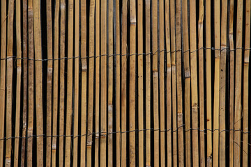 Sliced bamboo slats woven together by wire.  Fence privacy screen. Ornamental fence divider. Reed garden decoration background.