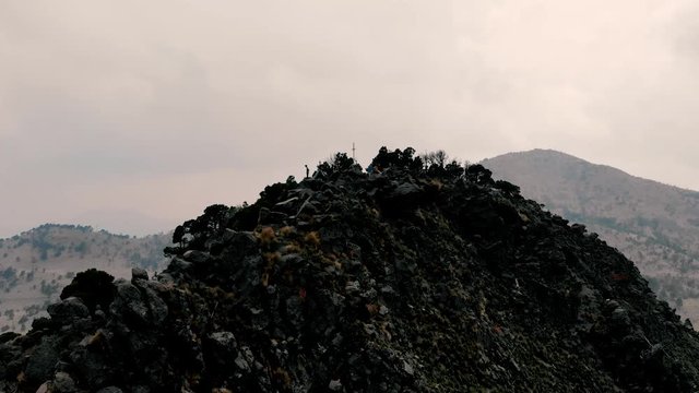 Camera moving away from 3 people at the Summit cross and dead cross at Ajusco vulcano in Mexico