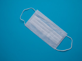 White medical face mask isolated on a blue background top view with copy space.