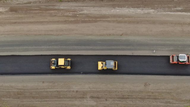 Roller machines make new asphalt roads. The asphalt paver squeezes hot asphalt.