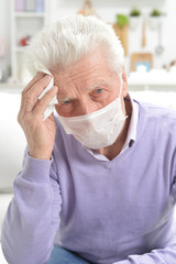 Portrait of sad sick senior man with facial mask