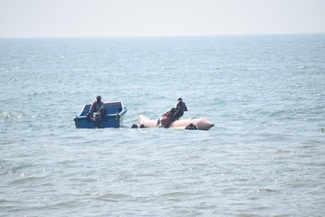 Group of young people riding banana boat water sport.Anjuna beach,Goa,India.14 December 2019.