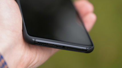 black smartphone with usb-c connector. in hands and blurred background.
