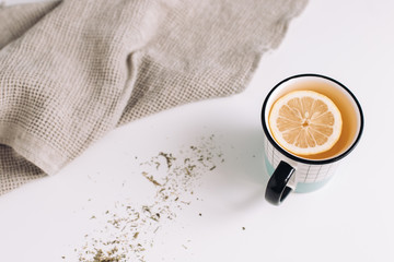 A cup of tea with lemon on white table, composition with towel