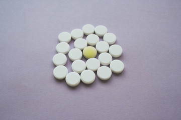 Round white pills and yellow one on a purple background in the middle of shot, isolated
