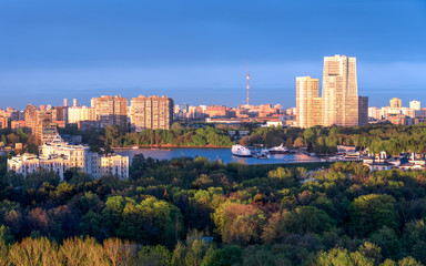 Fototapeta na wymiar Moscow city skyline, panoramic view. Amazing colourful scenery of the park, river with luxury yachts, sunlit buildings. 