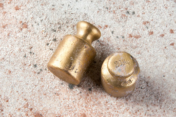Two antique bronze weights for scales on concrete background.