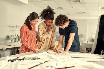 Look good with us. Young cheerful designers working together in a studio. Group of creative millennials sharing and discussing ideas