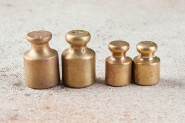 Four antique bronze weights for scales on concrete background.