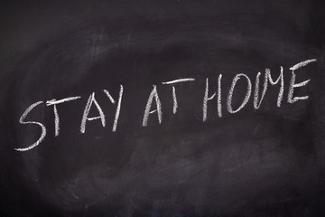 The inscription stay at home on the school blackboard. White letters on a black background in the classroom.