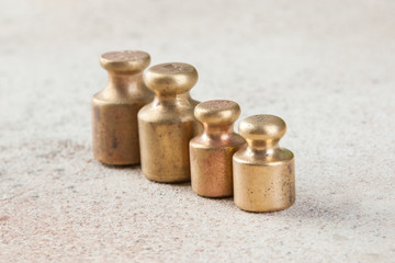 Four antique bronze weights for scales on concrete background.