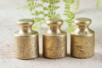 Three antique bronze weights for scales on concrete background.