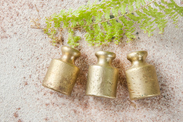 Three antique bronze weights for scales on concrete background.