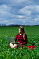 Naklejka na ściany i meble Joyful young girl on the grass with a laptop on her lap. He raised his hands up and laughed. Happiness in the lifestyle of a classical student. Work on the nature. Rest after a good working day.