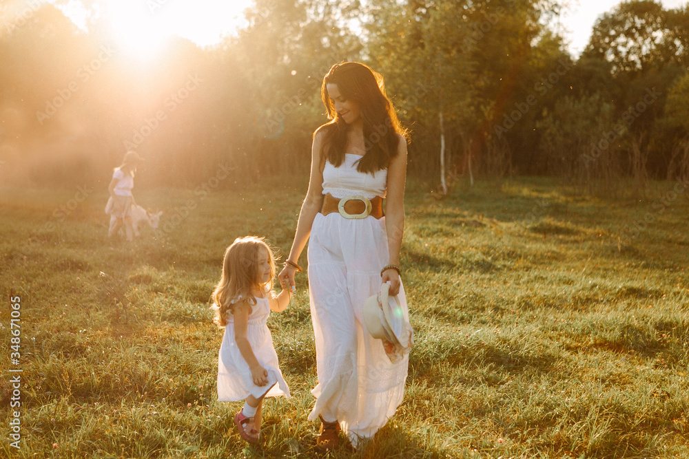 Wall mural family mom with children stand at sunset on a summer day at the farm