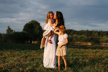 family mom with children stand at sunset on a summer day at the farm