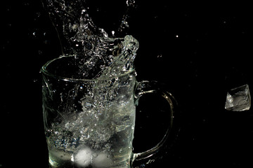 glass mug filled with water and ice with splash effect and black background