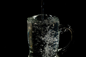 glass mug filled with water and ice with splash effect and black background