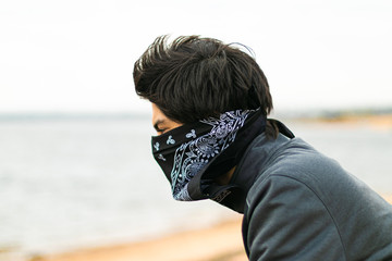 masked young man protecting himself from covid-19 on the coast of asunción paraguay