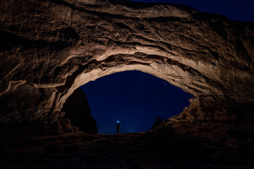 The North Window at Arches National Park. Standing inside The North Window wearing head lamp at night.