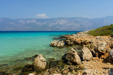 Fototapeta na wymiar Shore of the island in the Aegean Sea on a background of mountains