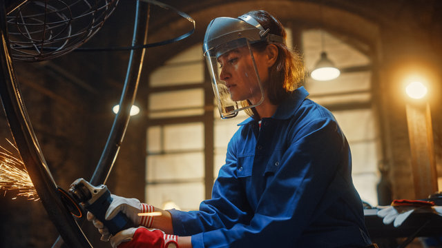 Close Up Portrait of Beautiful Female Fabricator in Safety Mask. She is Grinding a Metal Object and Flying Hot Sparks Reflect on the Mask. Empowering Natural Beauty Working in a Workshop.
