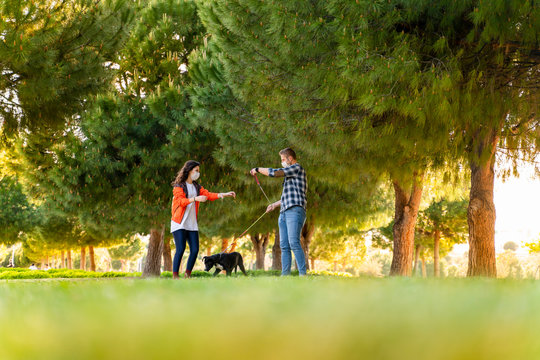 young couple wearing a protective mask is walking alone with a dog outdoors because of the corona virus pandemic covid-19