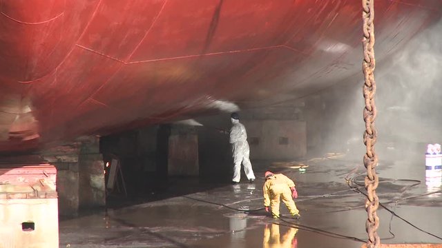 workers washing ship in dry dock shipyard
