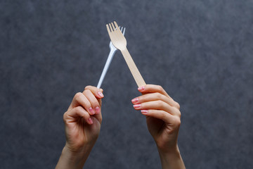 Zero waste concept. Wooden cutlery versus plastic cutlery. Eco-friendly disposable tableware made of bamboo wood and paper on a gray background. Caring for the environment. Recycling problem.