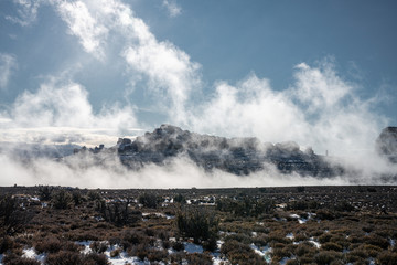 Clouds rising at Arches National Park in snow when sun is rising.