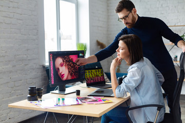 Professionals - photographer and retoucher. Retouching images on a graphics tablet. Teamwork in a...