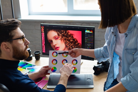 Professionals - photographer and retoucher. Retouching images on a graphics tablet. Teamwork in a professional photo studio.