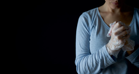 Woman prays with faith to GOD. Religion care during the pandemic crisis. Hands in disposable gloves are folded in prayer. Online church worship.