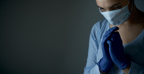 A woman in a medical protective mask prays with faith to GOD. Religion care during the pandemic...