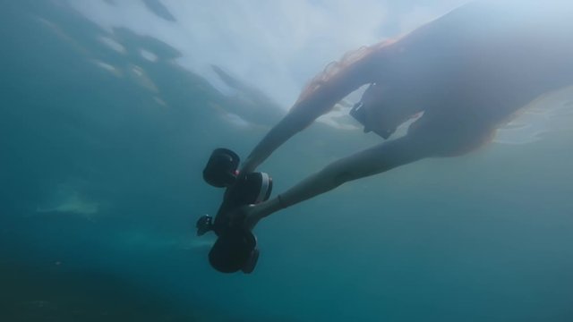 Beautiful lady in dress riding underwater scooter in ocean