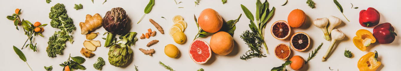 Immunity boosting plant foods. Flat-lay of ginger, turmeric, kale, artichoke, citrus fruit, herbs, garlic, pepper over white background, top view, wide composition. Healthy, virus defeating ingredient