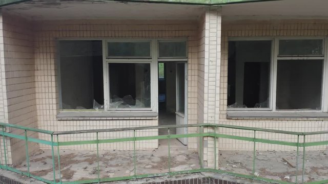 Aerial side view of an abandoned hotel (motel of vacation retreat) with broken windows on the balconies. Low angle shot