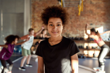 Stronger and smarter. Portrait of a boy smiling at camera before warming up, exercising together with other kids and trainer in gym. Sport, healthy lifestyle, active childhood concept