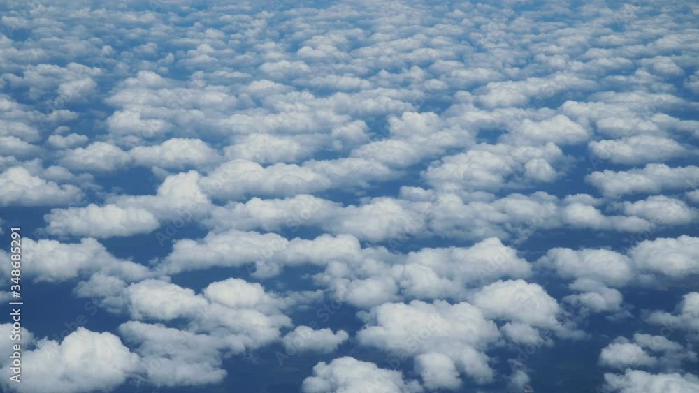 Wall mural aerial view above clouds from airplane window. tavelling by air background. real time footage.