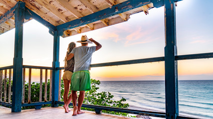 Couple contemplating the moment during the sunset from a terrace on a tropical island.