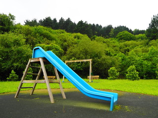 tobogan azul en un parque infantil en medio de la naturaleza