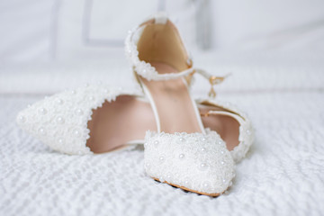Fototapeta na wymiar Beautiful pair of white wedding shoes with pearl decorations.