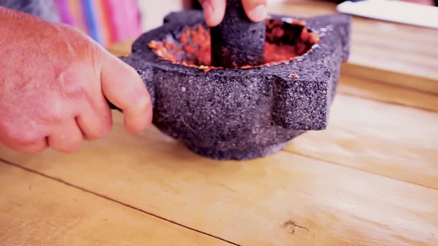 Using a morter to mash red hot chilli peppers