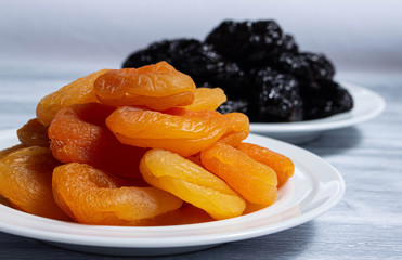 Dried apricots with prunes on white plates