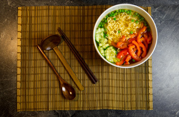 Vegan Japanese Ramen Noodle Soup with red bell pepper and cucumber served in a white bowl with...