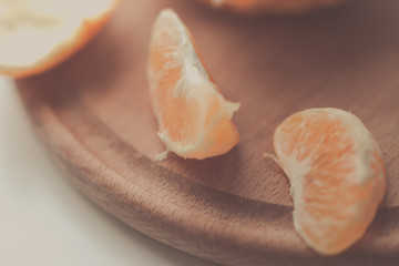 two orange mandarin slices on a wooden board.