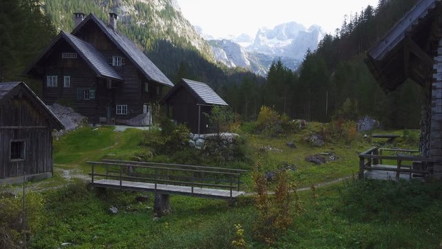 girl hiker walking by the tourist mountain trail along the wooden huts on a meadow at the austrian Alps
