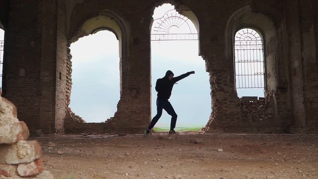 Man boxer in the hood trains beats in an abandoned building. Shadow Boxing on a beautiful background. Martial arts. Outdoor workout. Shooting on the Steadicam. Slow motion