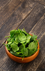 Spinach leafs in Wooden Bowl on wooden background with Copyspace
